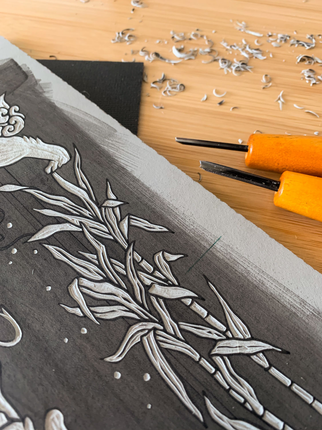 A closeup view of the partially carved grey linoleum block showing several carved stalks of sugar cane.