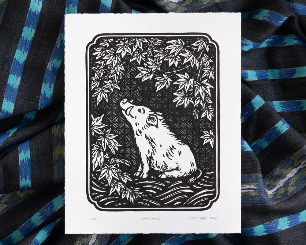 Black and white illustration of a boar sitting under a maple tree. The white paper sits on top of rumpled blue striped fabric.
