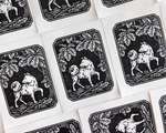 Multiple black and white blockprints tiled on a flat surface, each depicting a dog under a tree.